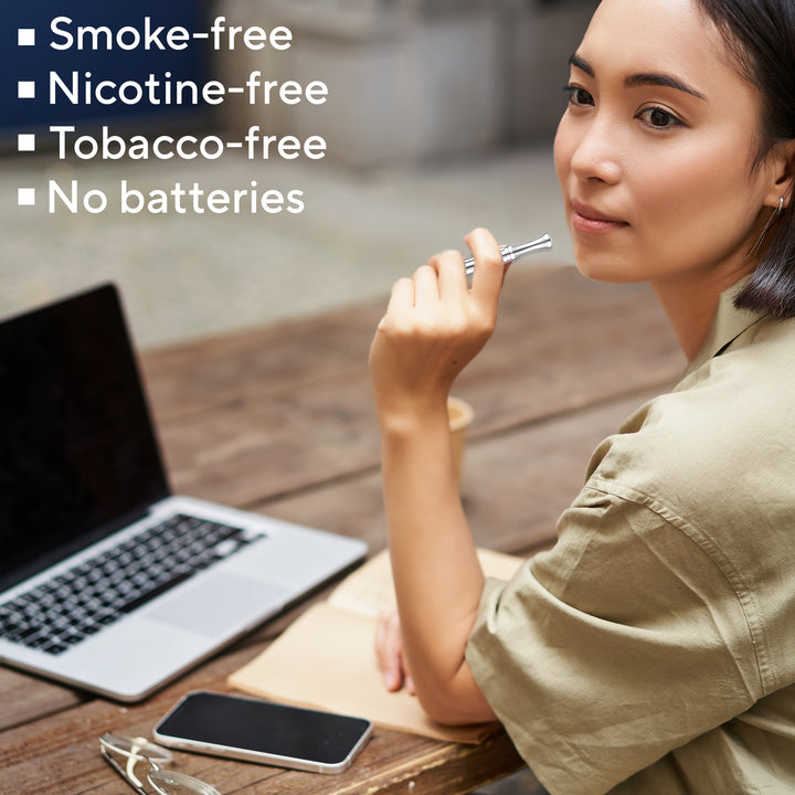 Woman using a smokeless inhaler necklace pen at a desk. No batteries, nicotine free, tobacco free alternative